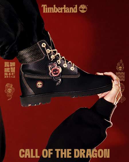 Image shows a bright, dark red background which features a closeup of a Timberland 6-inch boot in black leather with gold accents and gold dragon hangtags. Faint gold Chinese characters are visible in the center of the image.